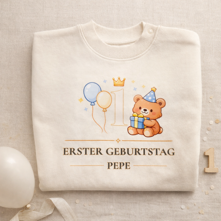 Beiges Baby Sweatshirt zum ersten Geburtstag mit niedlichem Bären, Geschenkbox, Partyhut und Ballons neben der Zahl 1. Darunter steht „Erster Geburtstag“ mit personalisiertem Namen. Ein liebevolles personalisiertes Baby Geschenk für Jungen oder Mädchen zum 1. Geburtstag.