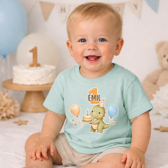 Baby T-Shirt beige mit Dino Motiv und Name Mateo im Geburtstagsdesign, süßes Outfit für ersten Geburtstag mit Deko Hintergrund und Torte