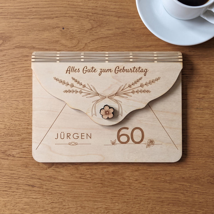 Geschenk zum runden 60. Geburtstag: Holzumschlag mit Motiv Lavendel, schlanken Lavendelzweigen mit Schleife. Name JÜRGEN über drei Herzen und die 60, graviert in 3 mm Lindensperrholz, neben einer Tasse Kaffee.