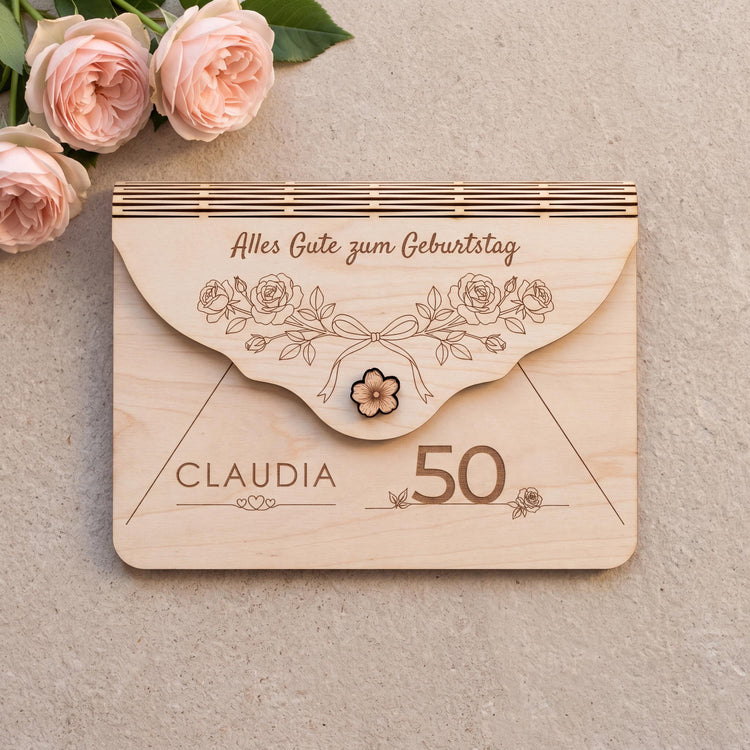Personalisierter Holzumschlag zum Geburtstag mit Motiv Rosen, einem Bogen aus Gartenrosen mit Schleife. Graviert: Alles Gute zum Geburtstag, Name CLAUDIA über drei Herzen und die Zahl 50. Größe 170 x 120 mm.