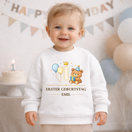 Personalisiertes Baby Sweatshirt zum ersten Geburtstag mit niedlichem Bären, Ballons und Krone neben der Zahl 1. Auf dem cremefarbenen Kinderpullover steht „Erster Geburtstag“ mit individuellem Namen. Ein liebevolles Geschenk und Outfit für Babys zur ersten Geburtstagsparty.