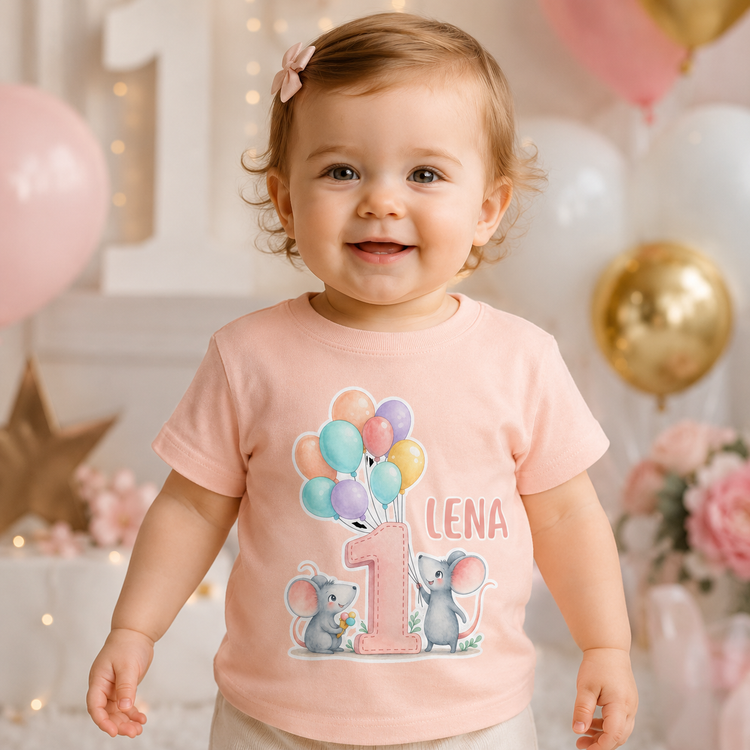 Kleinkind trägt ein pfirsich personalisiertes T-Shirt mit Name Lena, großer Zahl 1, bunten Ballons und niedlichen Mäusen. Perfektes Geschenk zum ersten Geburtstag für Mädchen, Geburtstagsparty oder Fotoshooting mit sanfter Deko im Hintergrund.